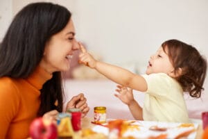 Cute little girl and mom spending good time painting autumn yellow leaves together